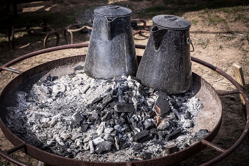 Still-life of two coffee pots keeping warm in the ashes of a fire.